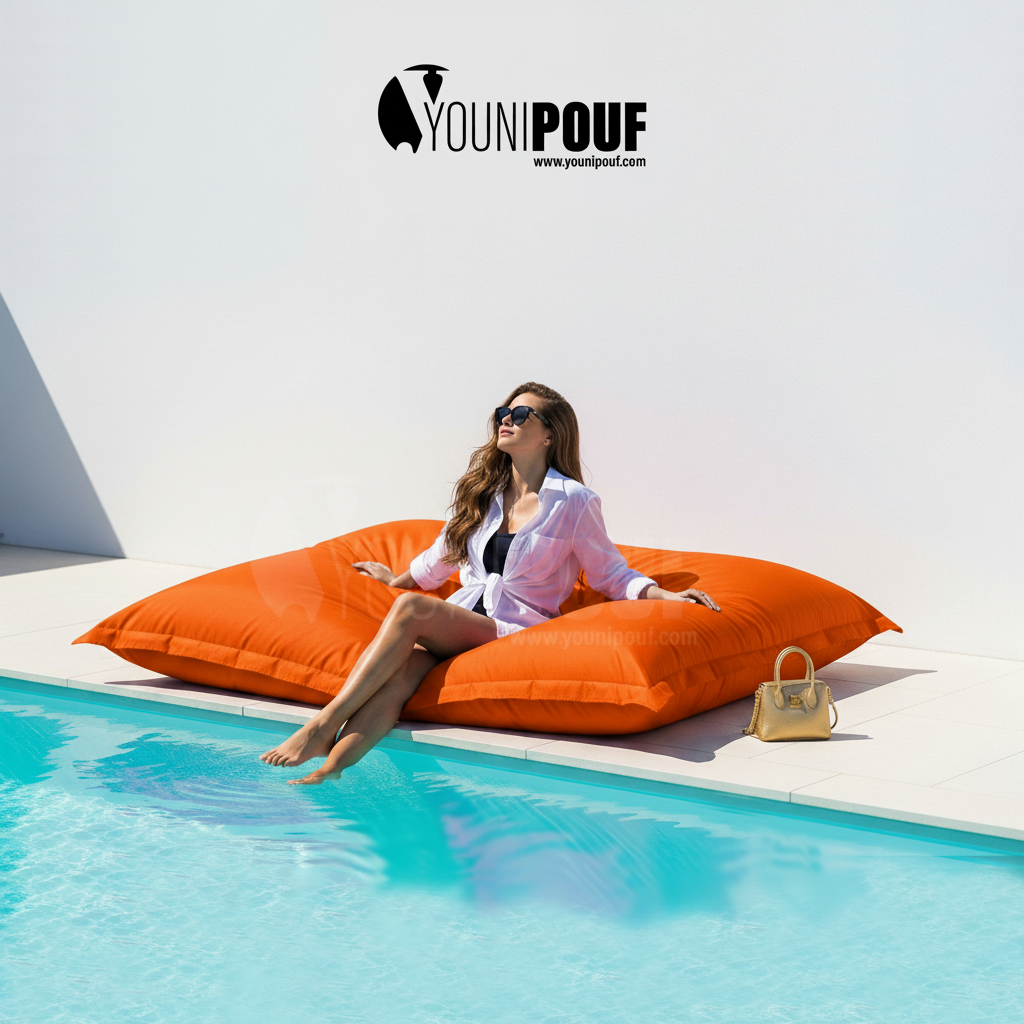 Pouf XXL orange YOUNIPOUF près d’une piscine, solution confortable pour aménager un espace détente extérieur.